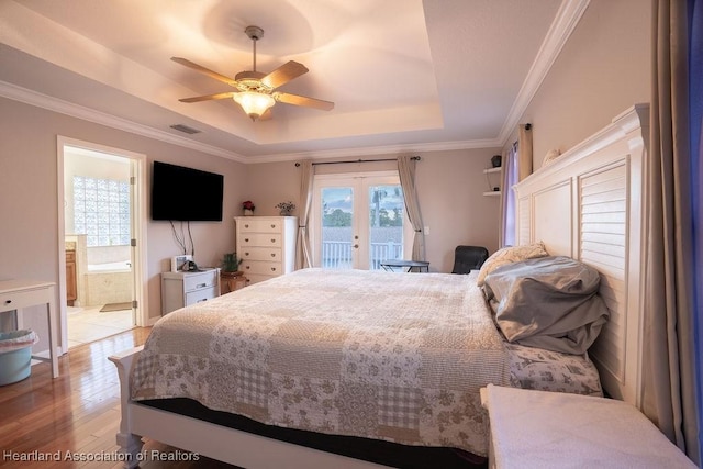 bedroom featuring access to outside, french doors, ensuite bathroom, ceiling fan, and a tray ceiling