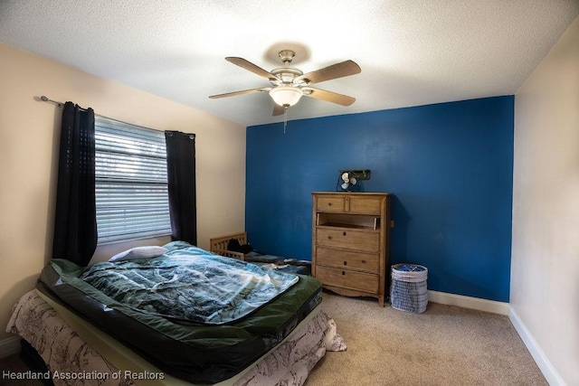 bedroom with a textured ceiling, light colored carpet, and ceiling fan