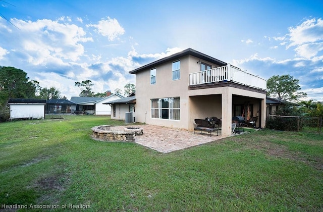 back of house featuring a yard, a patio area, a balcony, and a fire pit