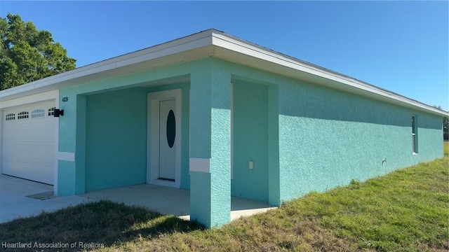 view of side of home featuring stucco siding, an attached garage, and a yard