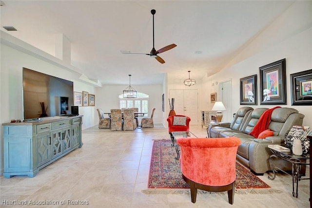 living room featuring lofted ceiling, light tile patterned floors, and ceiling fan with notable chandelier