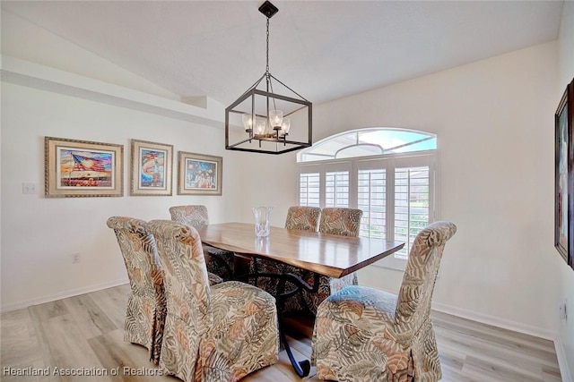 dining area with a chandelier, light wood-type flooring, and vaulted ceiling