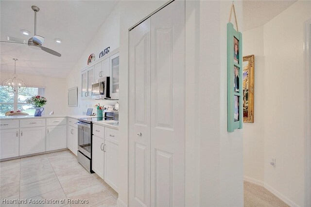 kitchen featuring white cabinets, ceiling fan with notable chandelier, stainless steel appliances, and vaulted ceiling