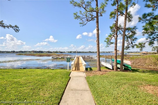 dock area with a lawn and a water view