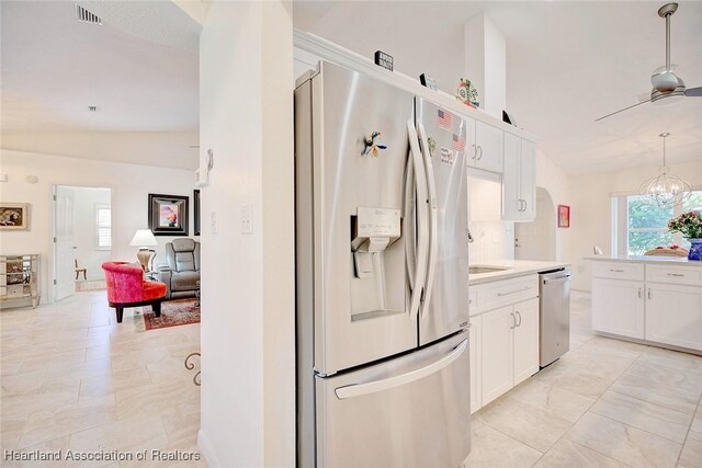 kitchen featuring ceiling fan with notable chandelier, stainless steel appliances, pendant lighting, white cabinets, and lofted ceiling