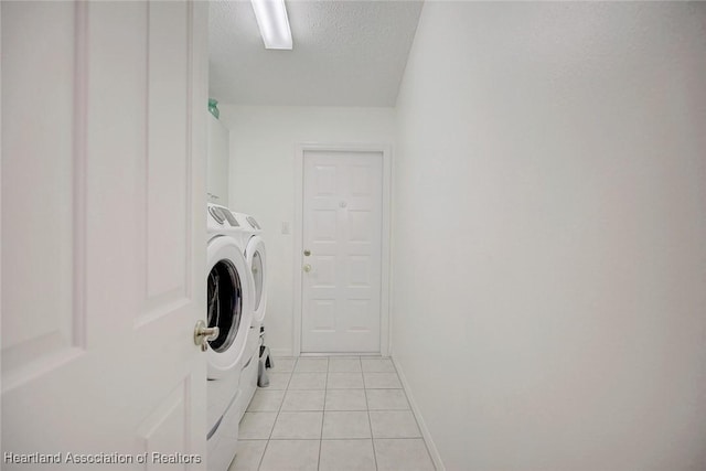 laundry room featuring washer and dryer, light tile patterned floors, and a textured ceiling