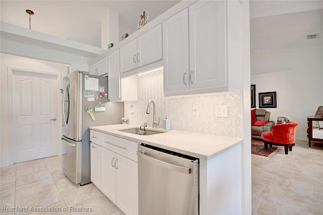 kitchen featuring white cabinets, appliances with stainless steel finishes, decorative backsplash, and sink