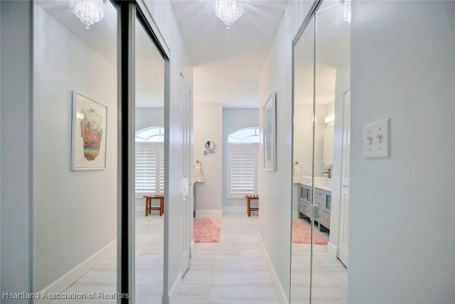 corridor featuring a chandelier and a textured ceiling