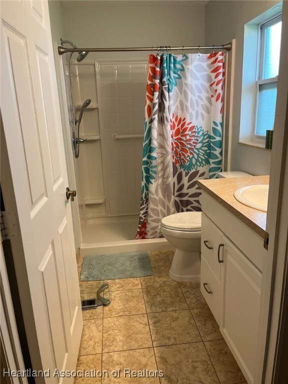 bathroom featuring a shower with shower curtain, vanity, toilet, and tile patterned flooring