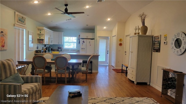 interior space featuring white appliances, lofted ceiling, white cabinets, hardwood / wood-style flooring, and ceiling fan