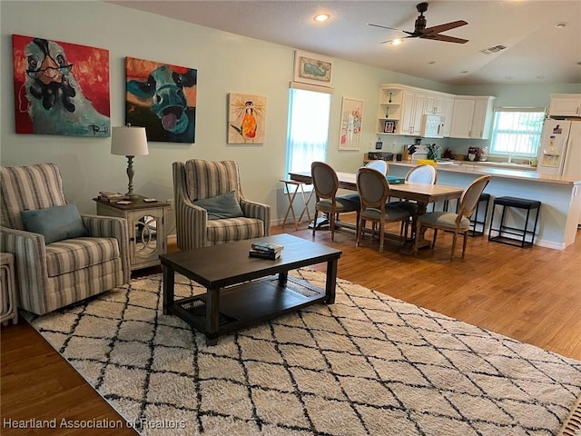 living room with vaulted ceiling, light hardwood / wood-style flooring, and ceiling fan