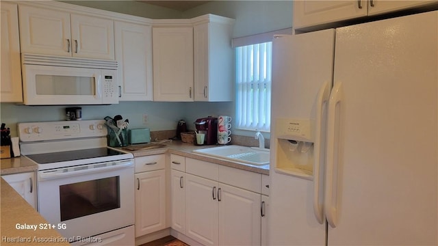 kitchen featuring sink, white cabinets, and white appliances