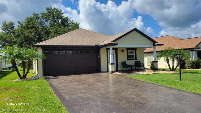 single story home featuring a front lawn, covered porch, and a garage