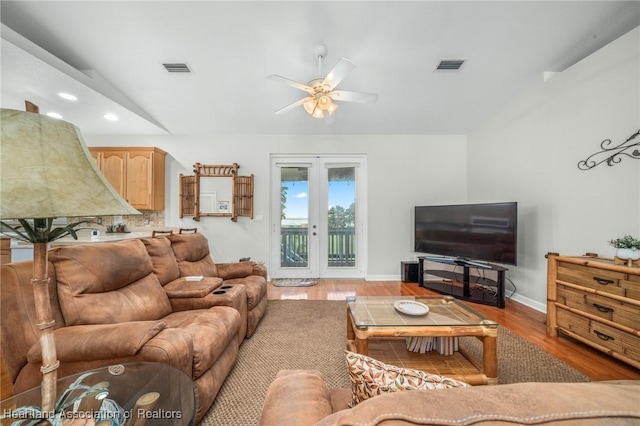 living room featuring ceiling fan, vaulted ceiling, light hardwood / wood-style flooring, and french doors