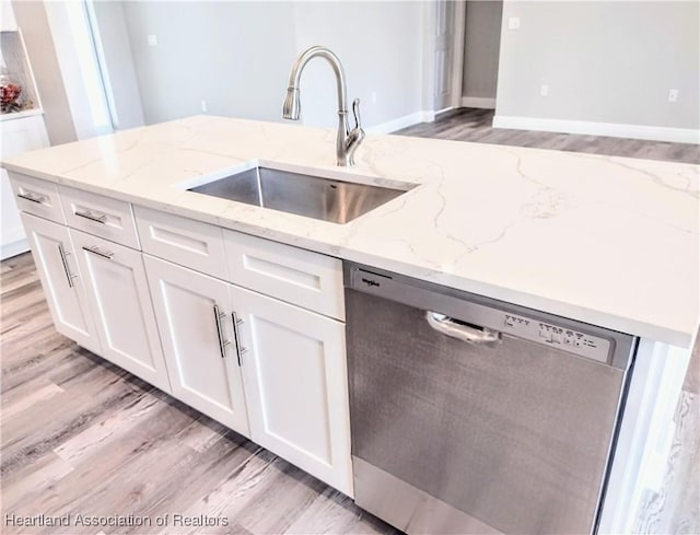 kitchen with white cabinets, dishwasher, light stone countertops, and sink