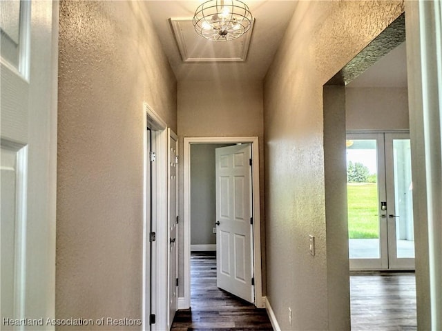 hallway with a notable chandelier, dark hardwood / wood-style flooring, a towering ceiling, and french doors