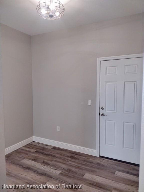 unfurnished room with hardwood / wood-style flooring and an inviting chandelier