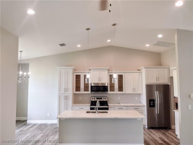 kitchen featuring light stone countertops, tasteful backsplash, pendant lighting, white cabinets, and appliances with stainless steel finishes