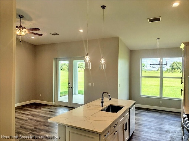 kitchen featuring light stone countertops, sink, stainless steel dishwasher, pendant lighting, and a kitchen island with sink