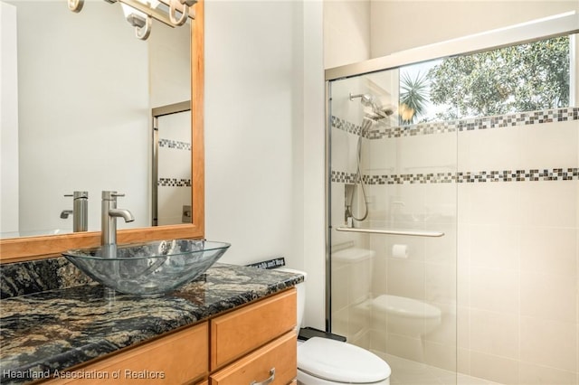 bathroom with toilet, an enclosed shower, and vanity