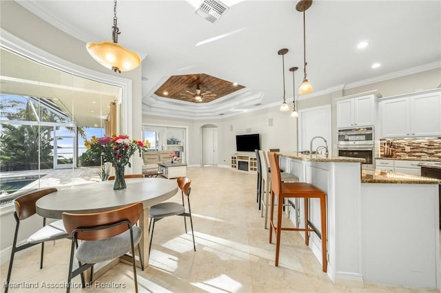 dining area with ceiling fan, a raised ceiling, and ornamental molding