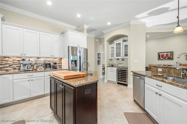 kitchen featuring stainless steel appliances, an island with sink, wine cooler, sink, and light stone counters