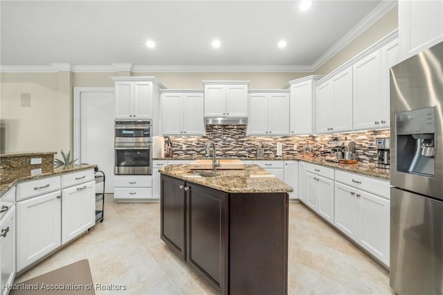 kitchen featuring white cabinets, ornamental molding, stainless steel appliances, and dark stone counters