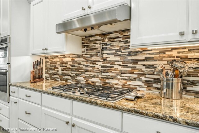 kitchen with decorative backsplash, stone countertops, and white cabinets