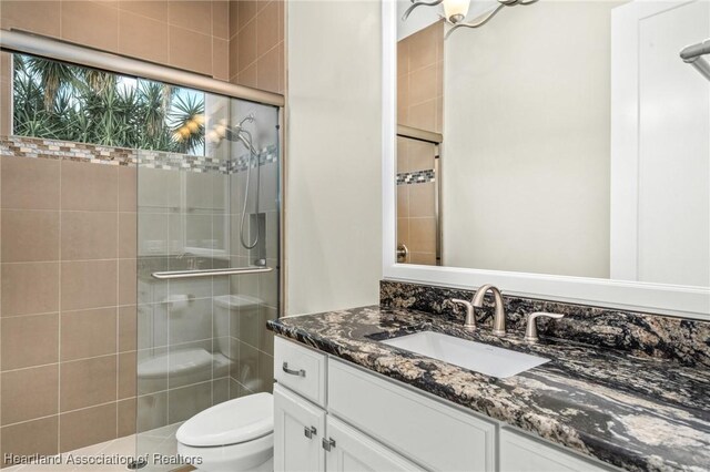 bathroom featuring toilet, an enclosed shower, and vanity