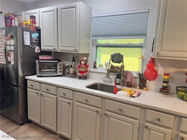4128 Capri St, Sebring, FL 33872 - kitchen featuring light countertops, a toaster, a sink, freestanding refrigerator, and light wood-style floors