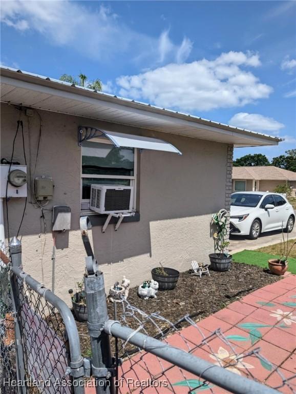 4128 Capri St, Sebring, FL 33872 - view of side of home featuring fence, stucco siding, and cooling unit