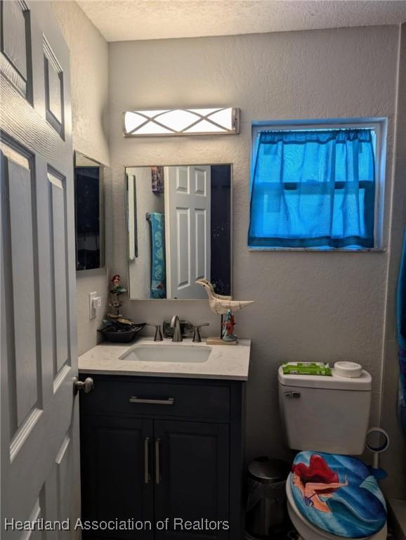 4128 Capri St, Sebring, FL 33872 - bathroom featuring vanity, a textured wall, toilet, and a textured ceiling