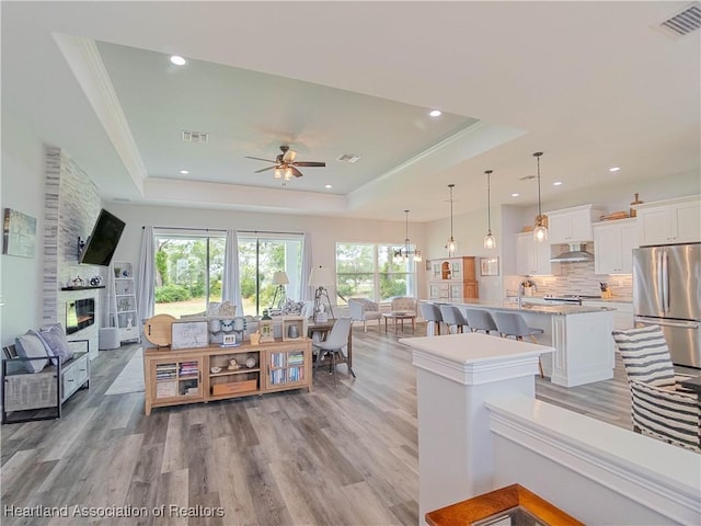 4936 Myrtle Dr, Sebring, FL 33872 - living room with a tray ceiling, plenty of natural light, light wood-type flooring, ceiling fan, and recessed lighting