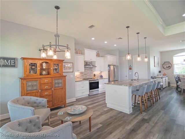 4936 Myrtle Dr, Sebring, FL 33872 - kitchen featuring stainless steel appliances, under cabinet range hood, dark wood-style floors, white cabinetry, and recessed lighting