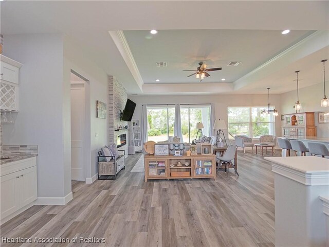 4936 Myrtle Dr, Sebring, FL 33872 - living area featuring a raised ceiling, a ceiling fan, light wood-style flooring, a large fireplace, and ornamental molding