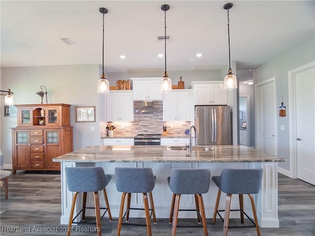 4936 Myrtle Dr, Sebring, FL 33872 - kitchen featuring appliances with stainless steel finishes, wall chimney range hood, dark wood-type flooring, white cabinets, and decorative backsplash