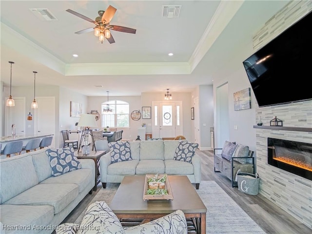 4936 Myrtle Dr, Sebring, FL 33872 - living room with wood finished floors, a tray ceiling, ornamental molding, a ceiling fan, and a fireplace