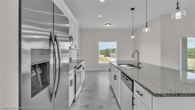 kitchen with stainless steel appliances, a kitchen island with sink, sink, white cabinets, and hanging light fixtures