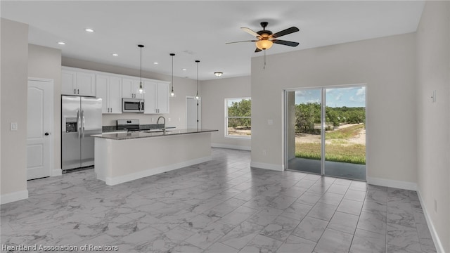 kitchen featuring white cabinets, a center island with sink, ceiling fan, appliances with stainless steel finishes, and decorative light fixtures