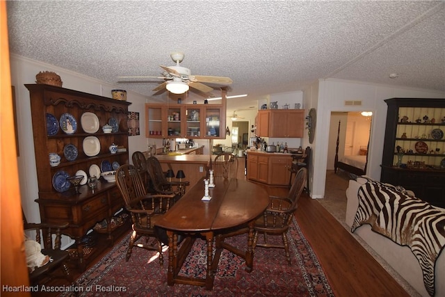 dining space with a textured ceiling, hardwood / wood-style flooring, vaulted ceiling, and ceiling fan