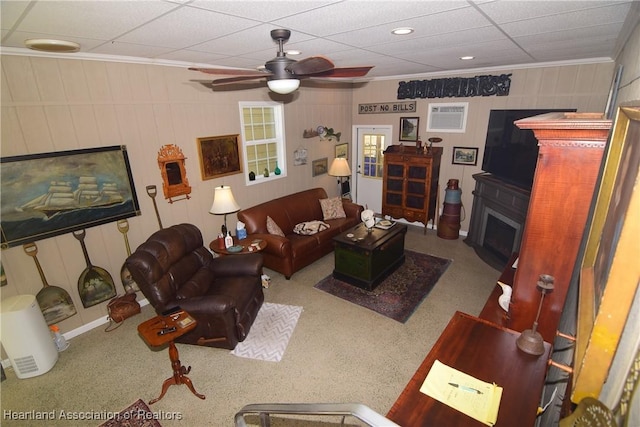 carpeted living room featuring an AC wall unit, ceiling fan, a fireplace, and ornamental molding