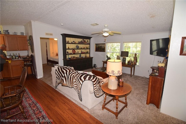 living room featuring a textured ceiling, hardwood / wood-style flooring, ceiling fan, and lofted ceiling