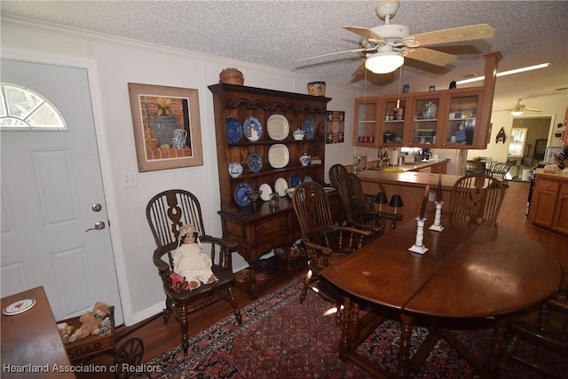 dining space featuring wood-type flooring, a textured ceiling, ceiling fan, and crown molding