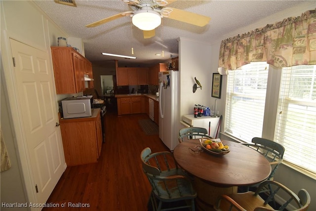 interior space featuring a textured ceiling, white appliances, plenty of natural light, and dark wood-type flooring