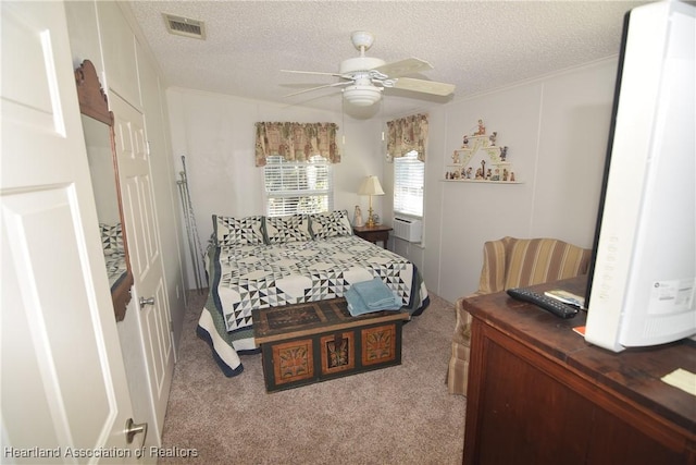 bedroom featuring ceiling fan, light colored carpet, a textured ceiling, and water heater