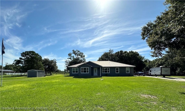 ranch-style home featuring a front lawn and a shed