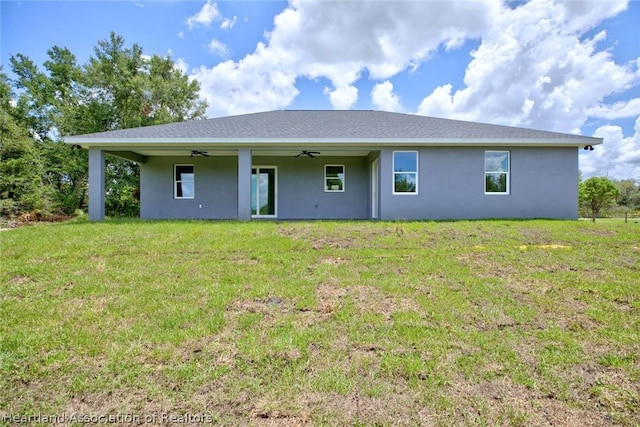 rear view of property with ceiling fan and a lawn