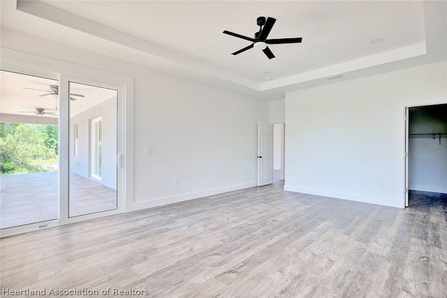 spare room featuring a tray ceiling and light hardwood / wood-style floors