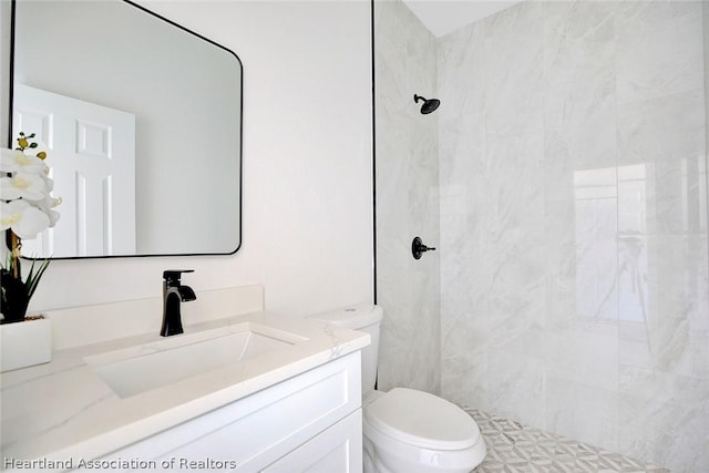 bathroom featuring vanity, toilet, and tiled shower