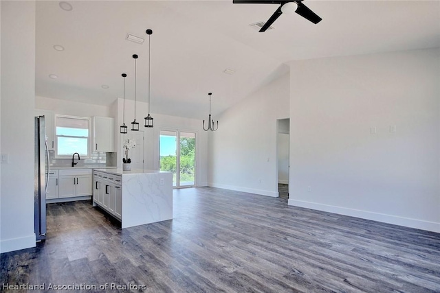 kitchen featuring white cabinetry, sink, a center island, pendant lighting, and vaulted ceiling